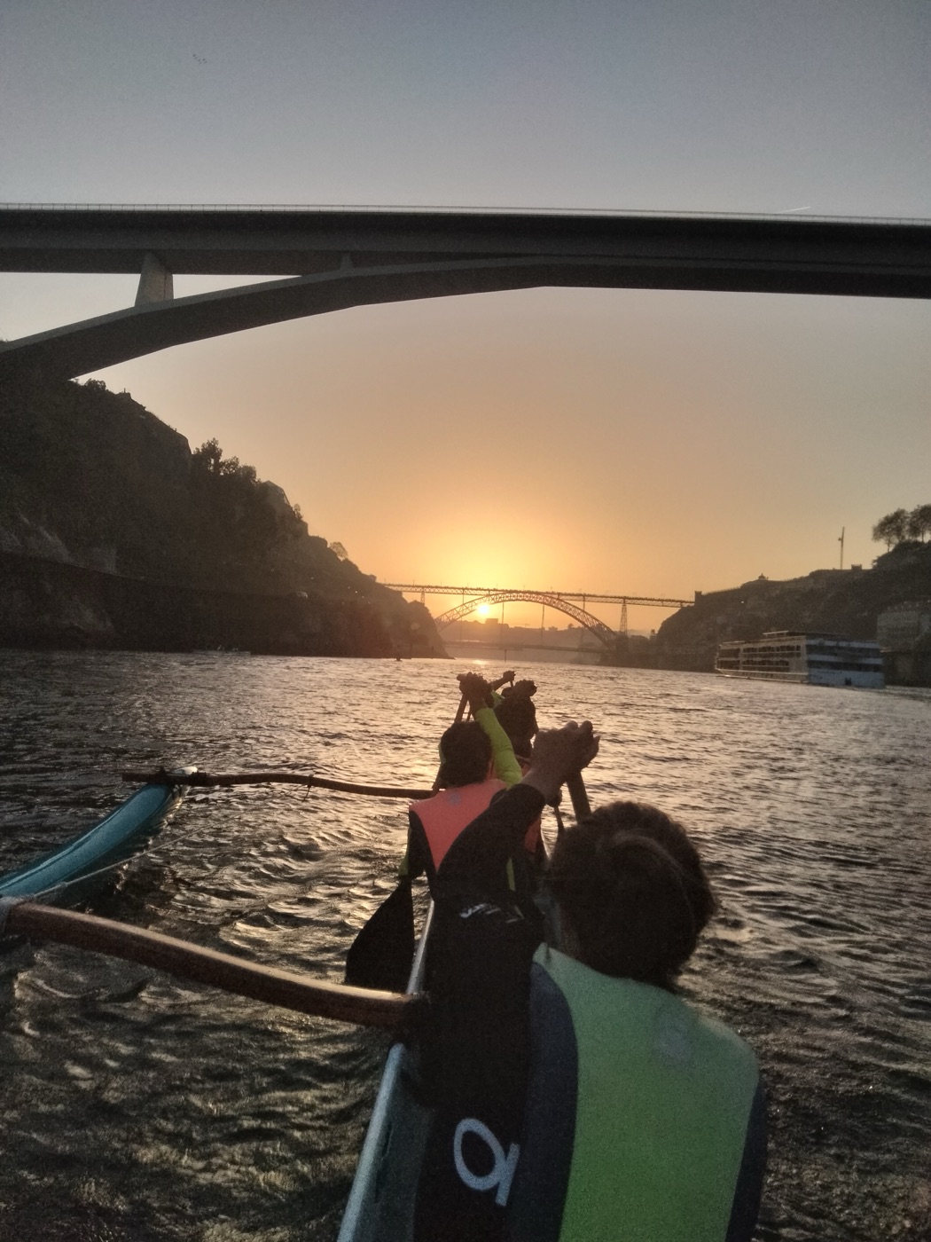 Equipa a remar ao pôr-do-sol sob a ponte do Douro